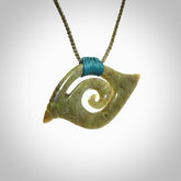 This photo shows a contemporary koru pendant carved from New Zealand Jade. We have added a Sea Moss Blue ridge-top binding with adjustable Olive Green cord.